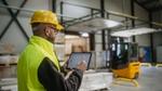 Dois homens com batas brancas e capacetes numa instalação industrial.